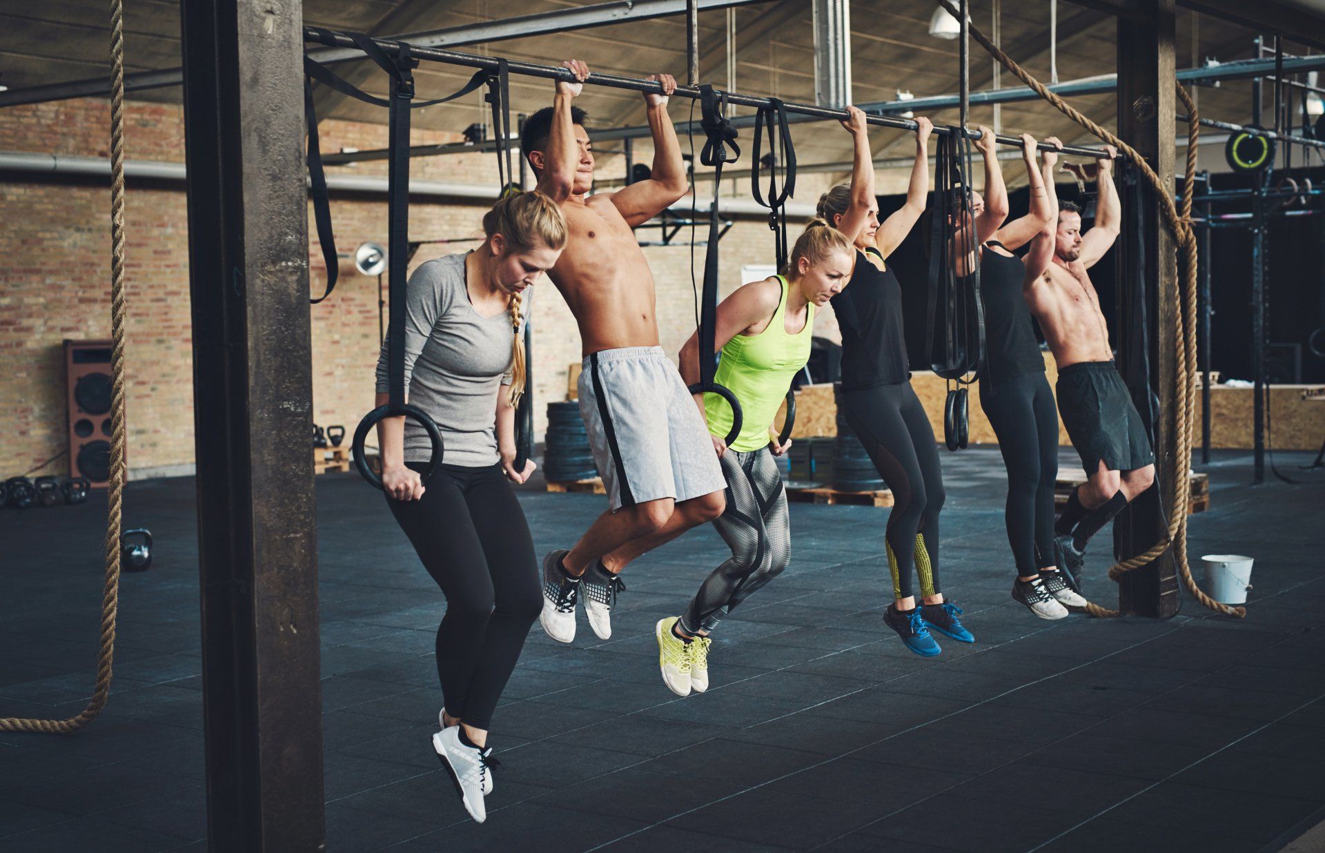 People exercising on rings and bars in a gym.