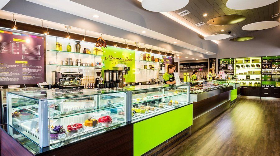 Inside a brightly lit chocolate shop with glass display cases, filled pastries, and a menu board.