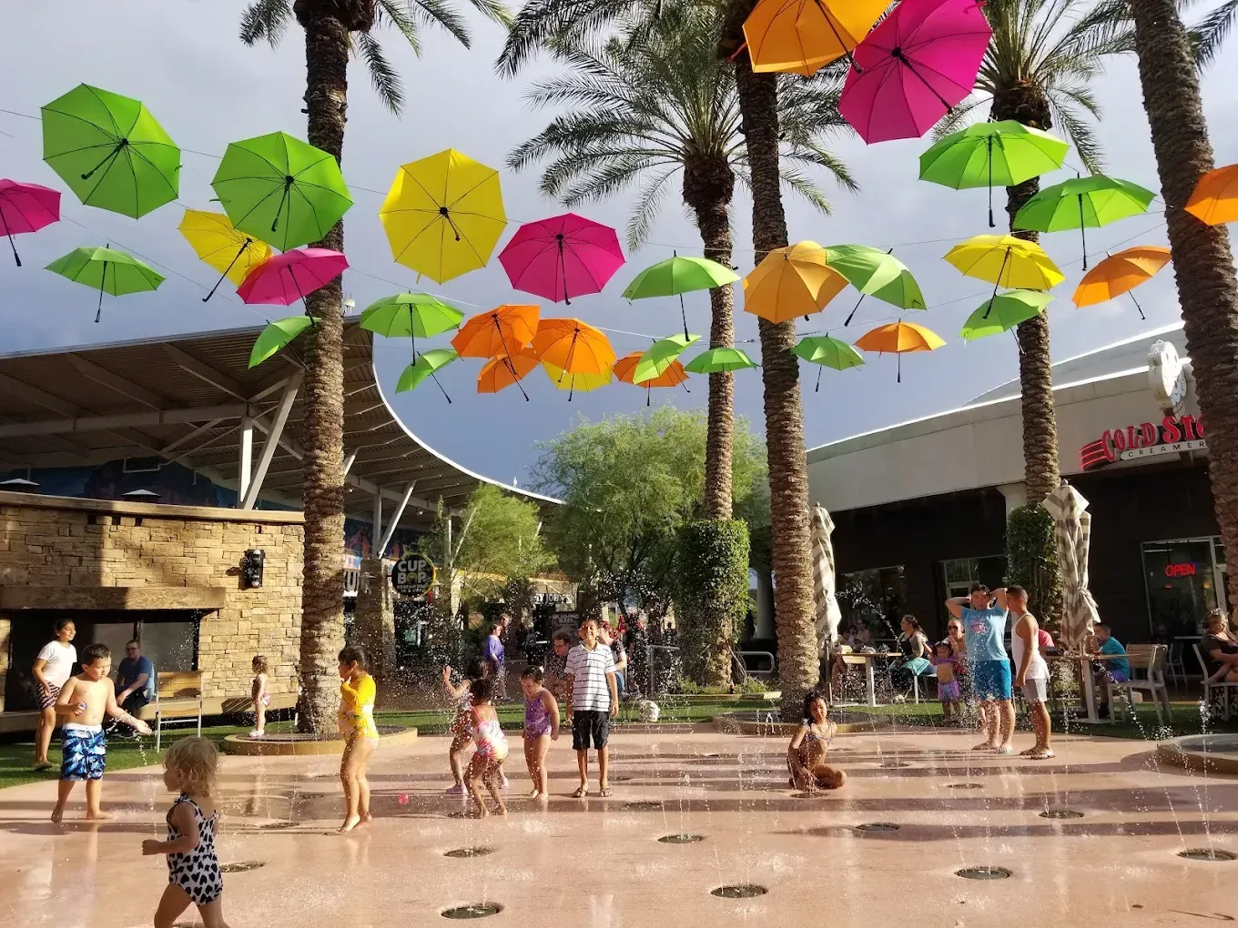Marketplace with shops, a central walkway, and a crowd of people under a covered walkway.