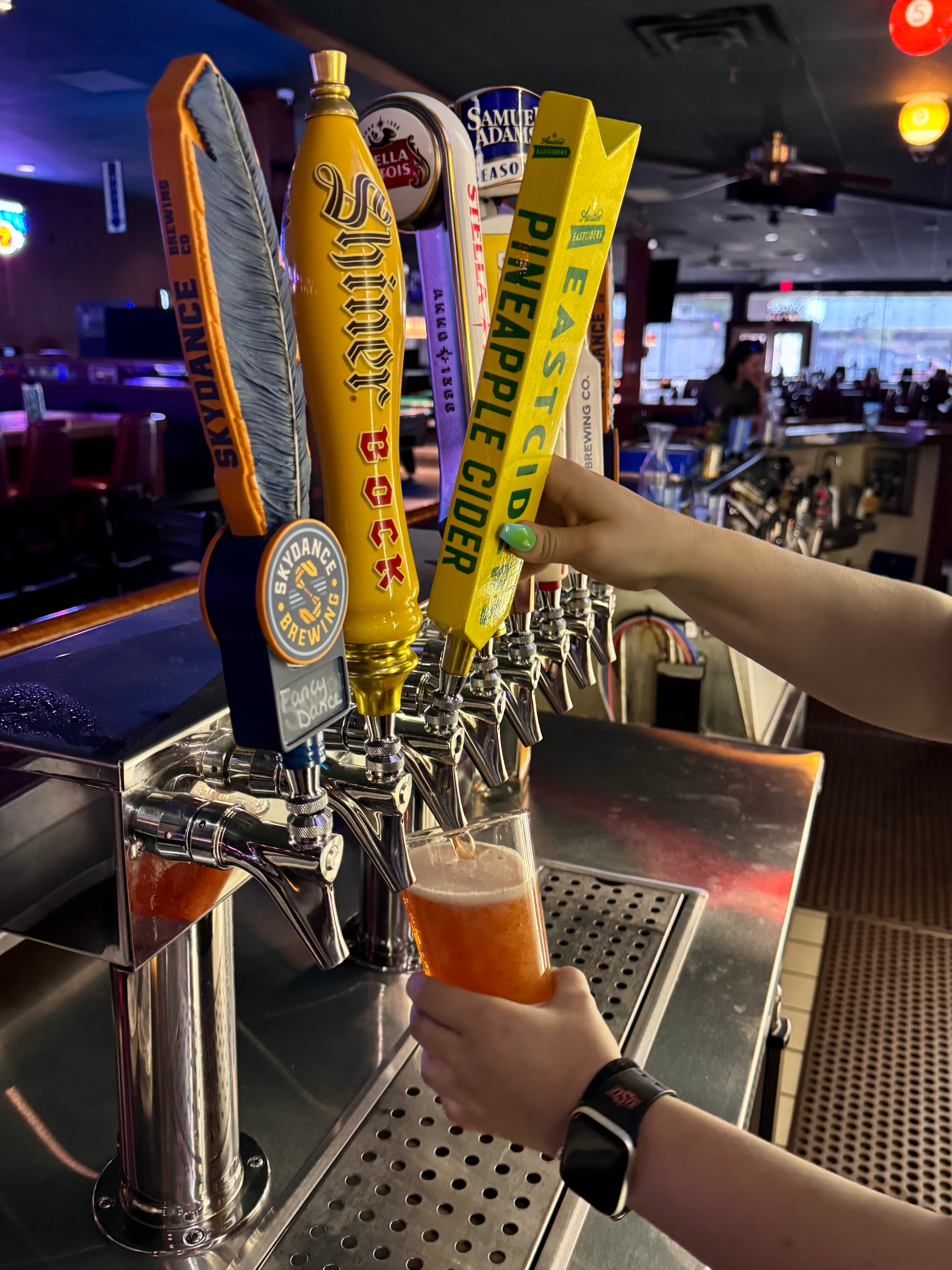 A person is pouring beer from a tap that says pineapple Eastcider