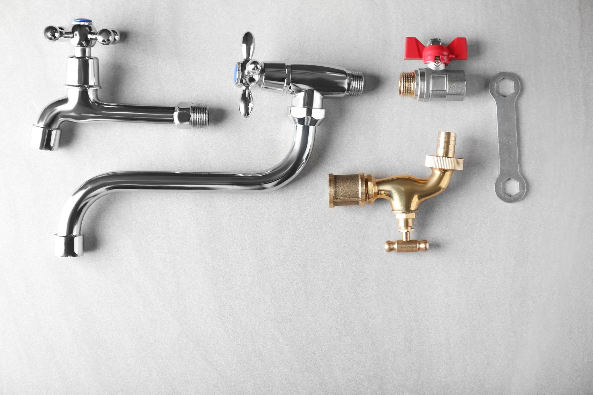 Various plumbing fixtures and a wrench on a white surface.
