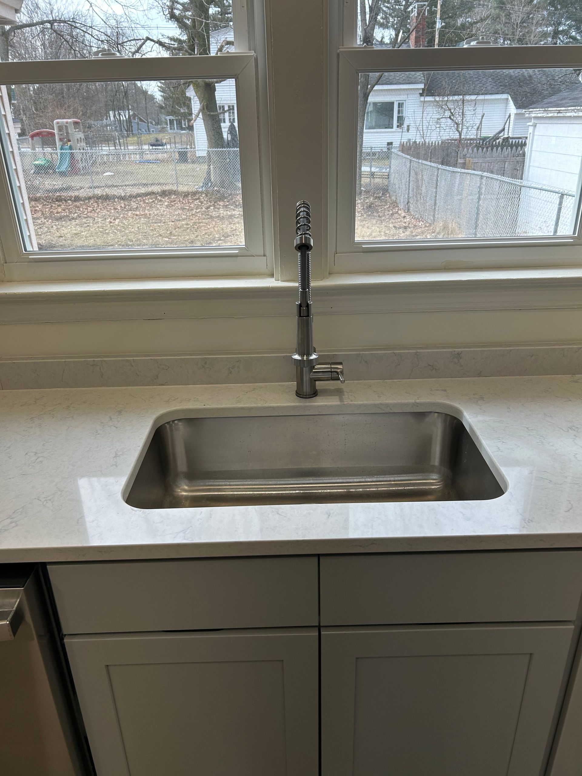 A kitchen sink with a faucet and a window in the background.