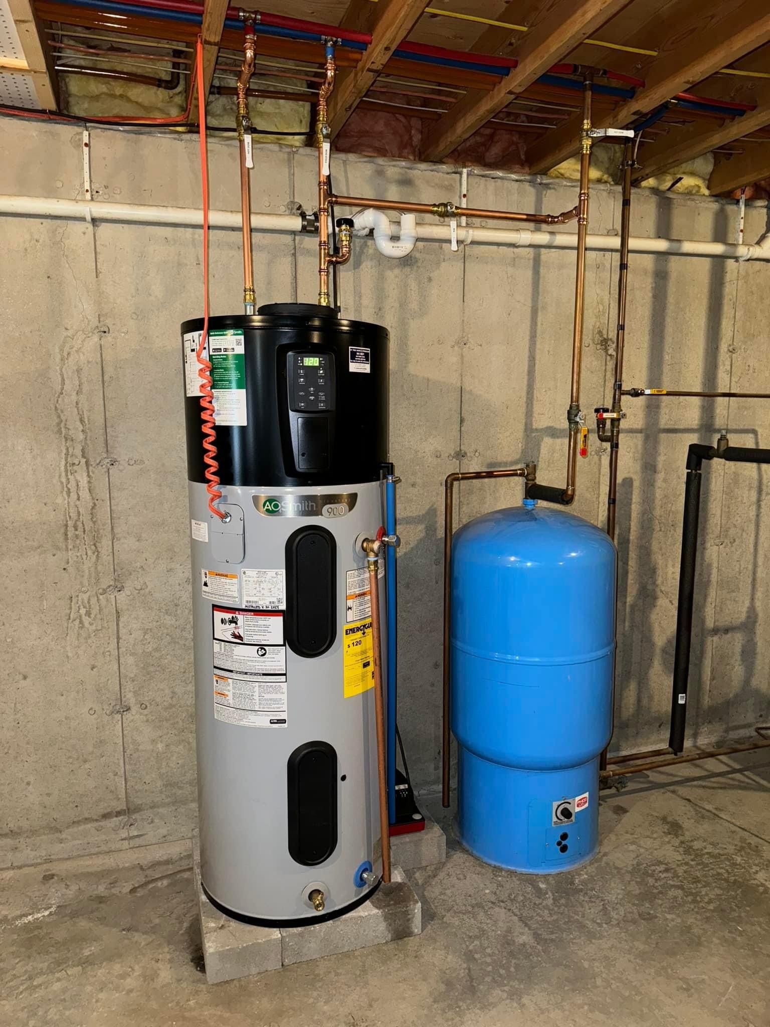 A water heater is sitting in a basement next to a blue tank.