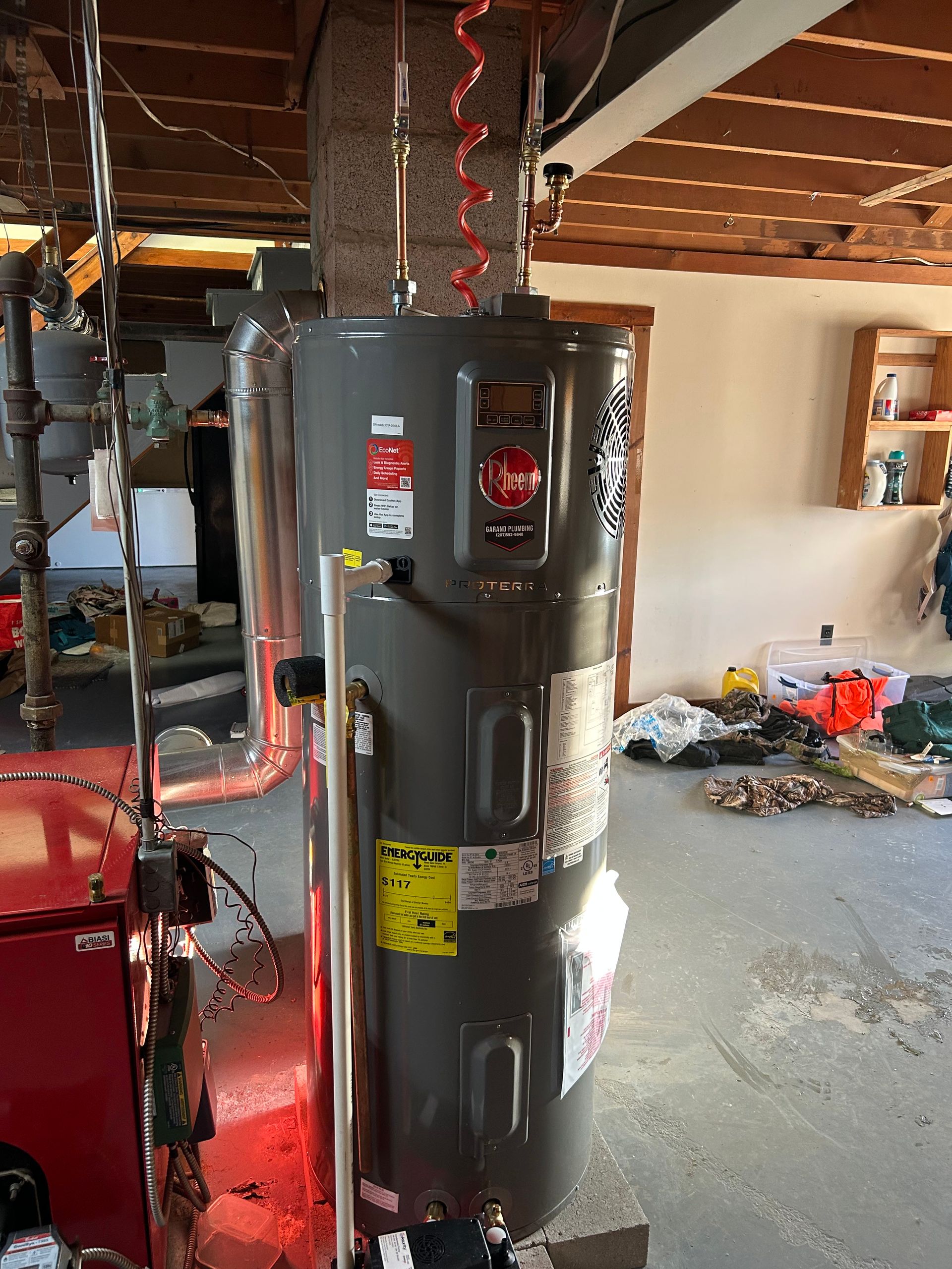 A large gray water heater is sitting in a messy room.