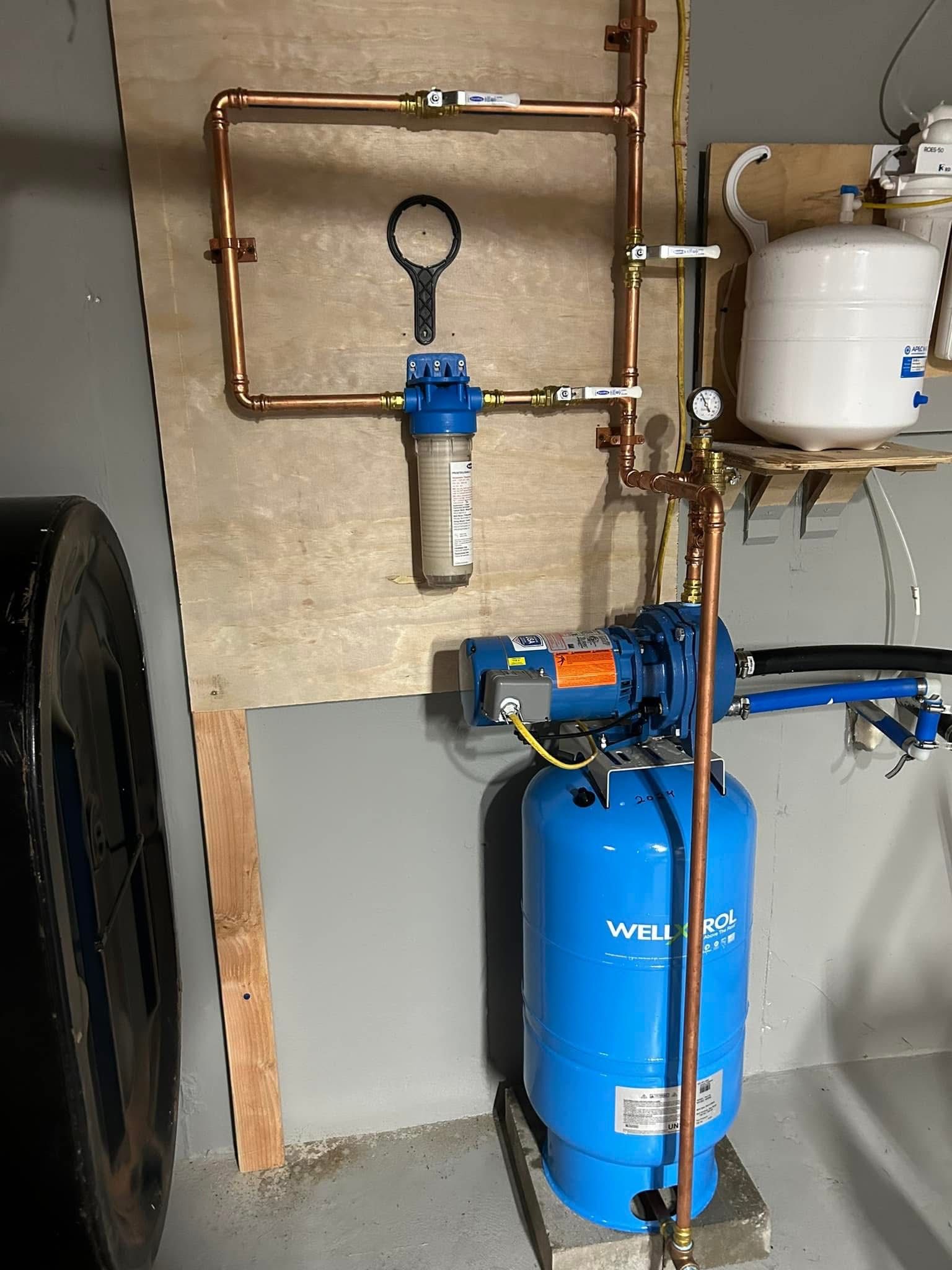 A blue water tank is sitting next to a copper pipe in a room.