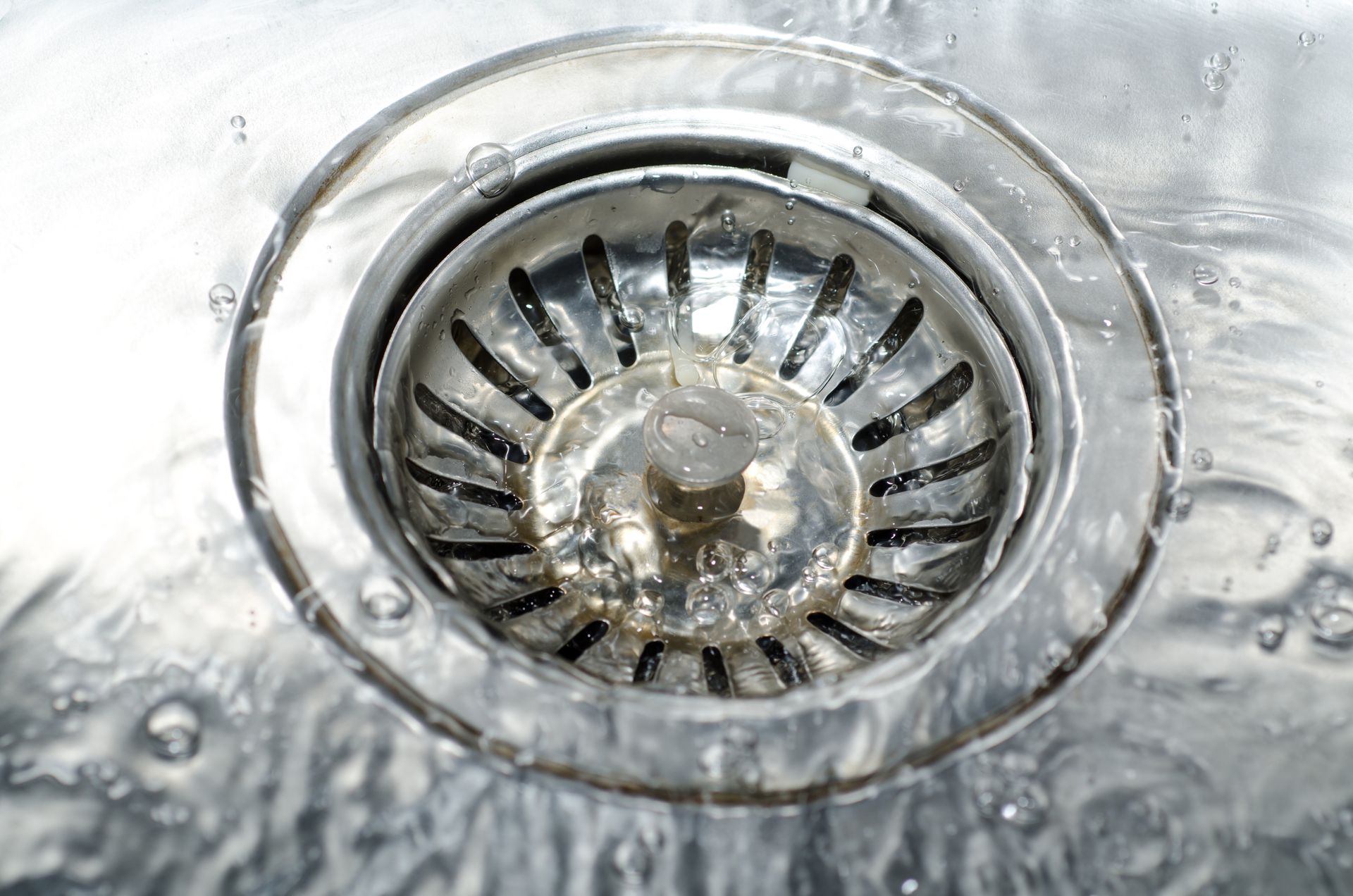 Water swirling down a shiny metal sink drain.