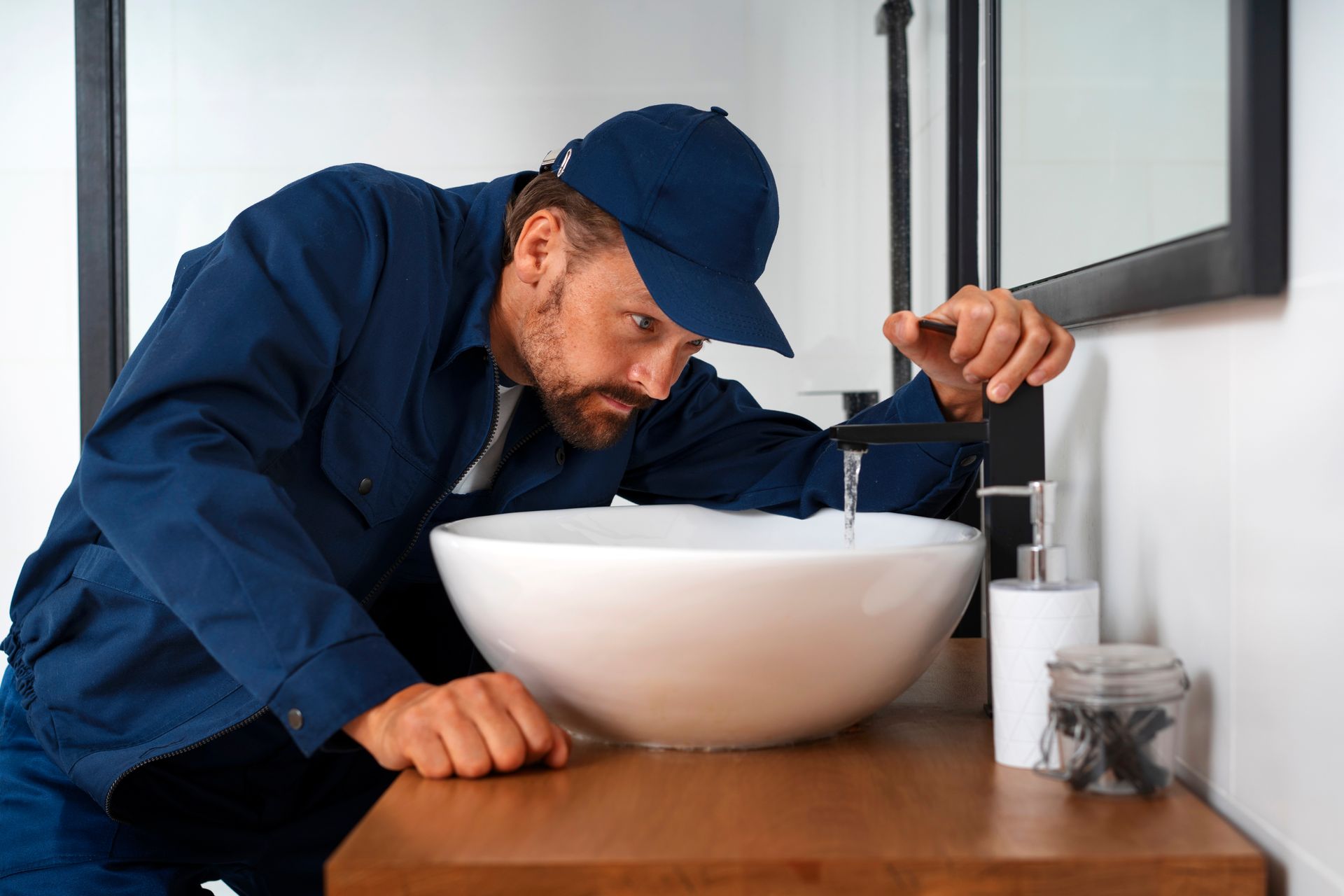 A plumber is fixing a sink in a bathroom.