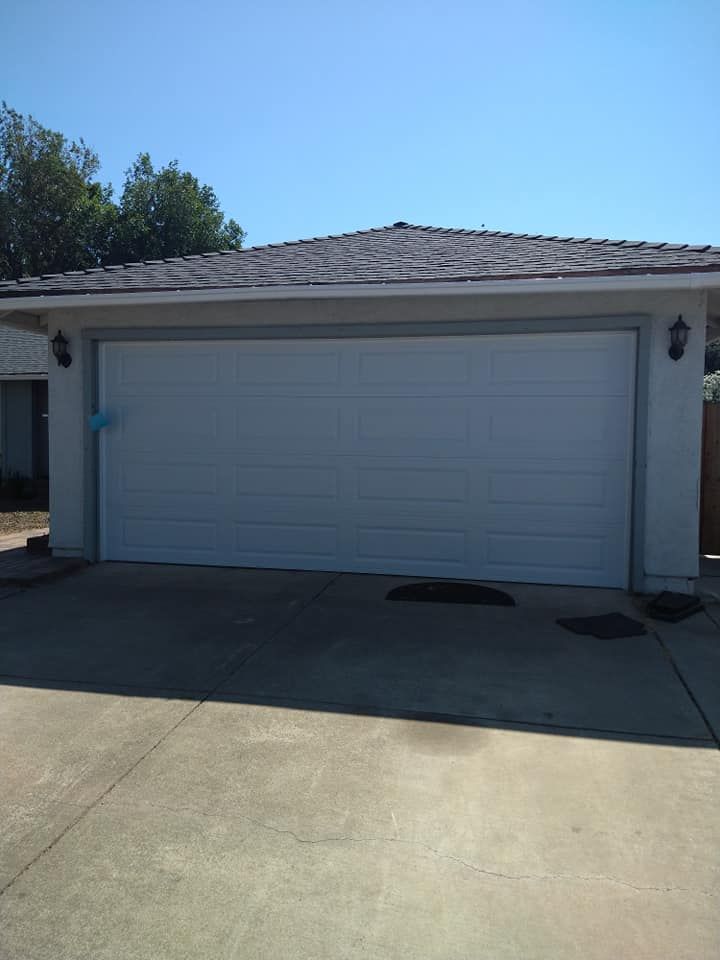A white garage door is open on a sunny day.