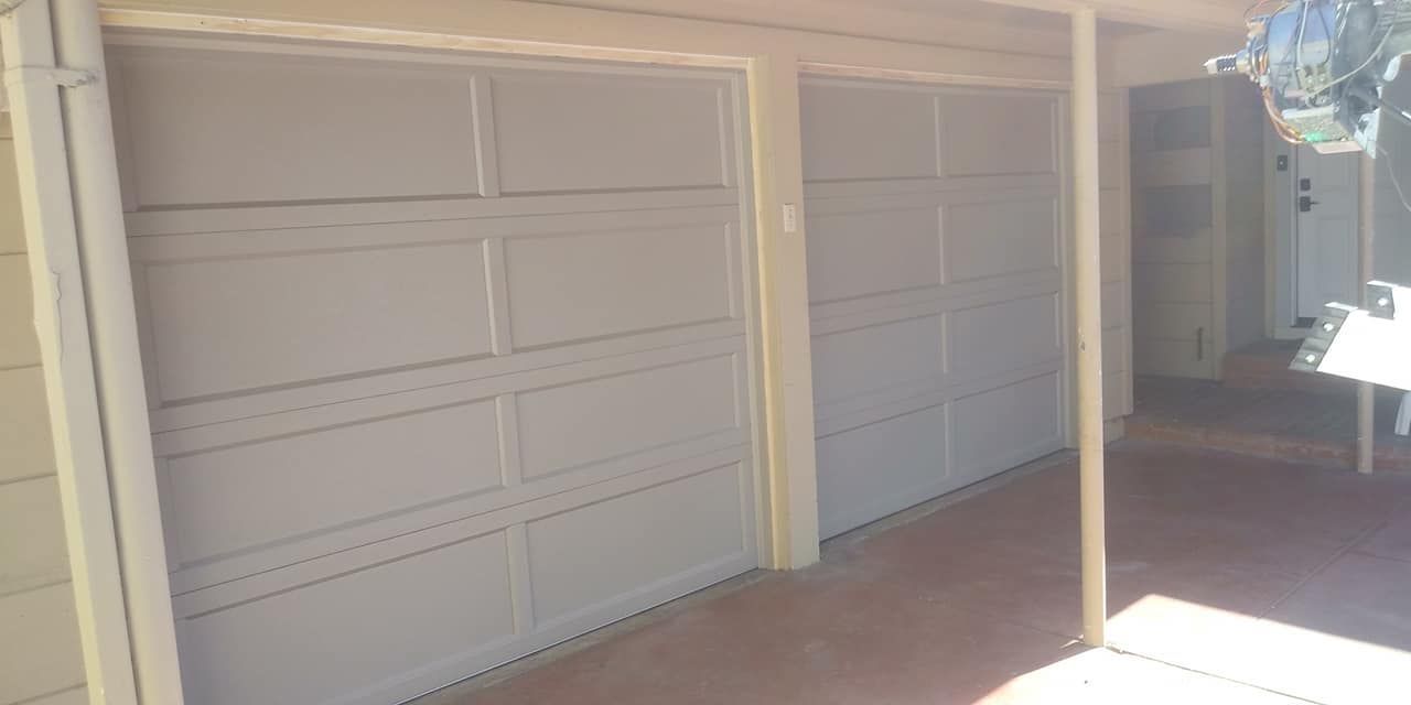 A couple of garage doors sitting next to each other on the side of a house.