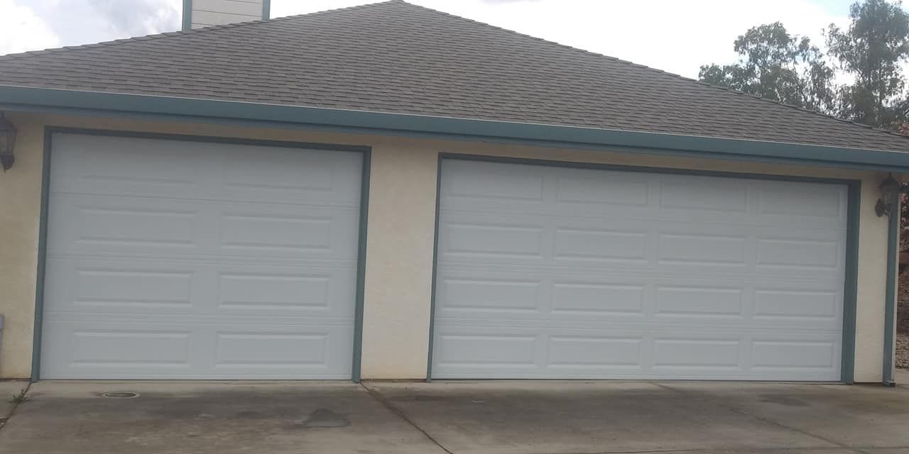 There are two garage doors on the side of a house.