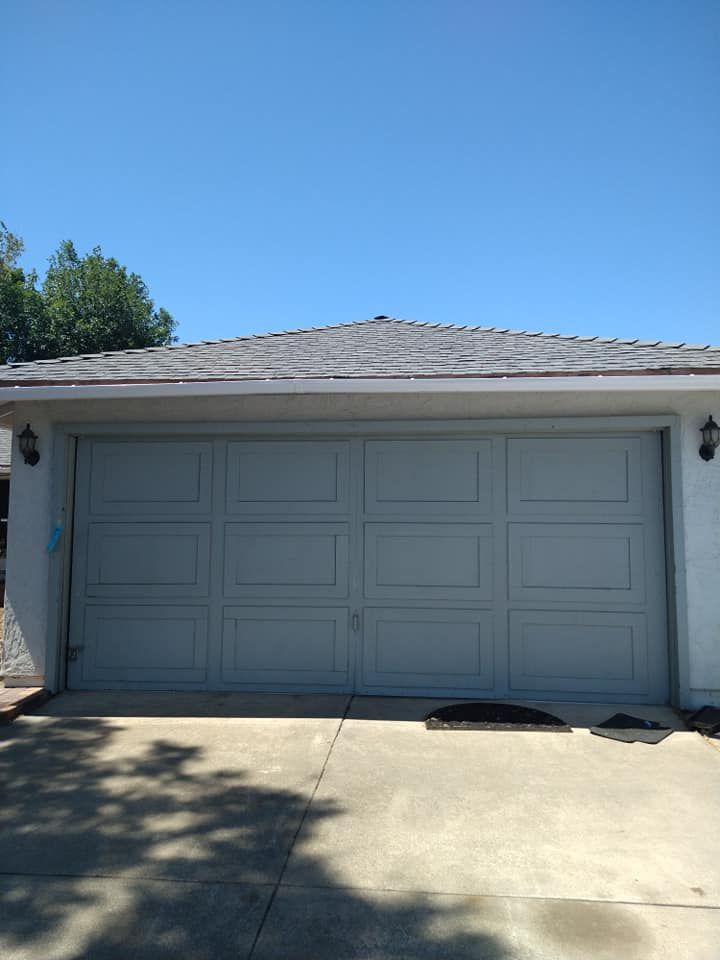A white garage door is open on a sunny day.
