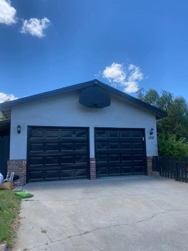 A white house with black garage doors and a blue sky in the background.