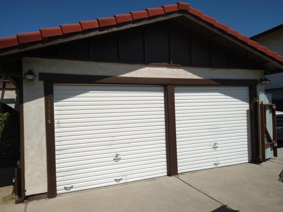 A white garage door with a red tile roof