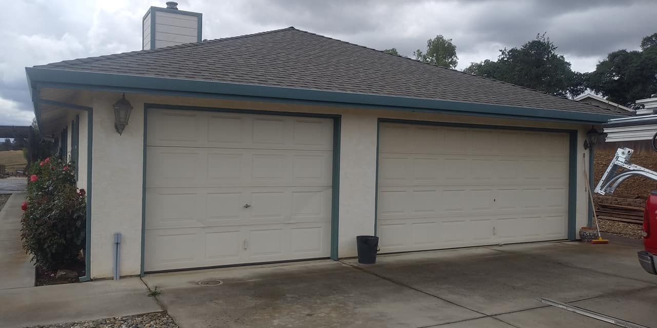 A white garage with two garage doors and a roof.