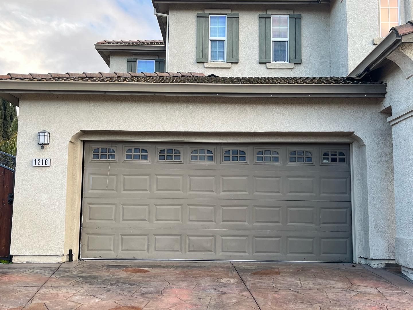 A garage door is open in front of a large house.