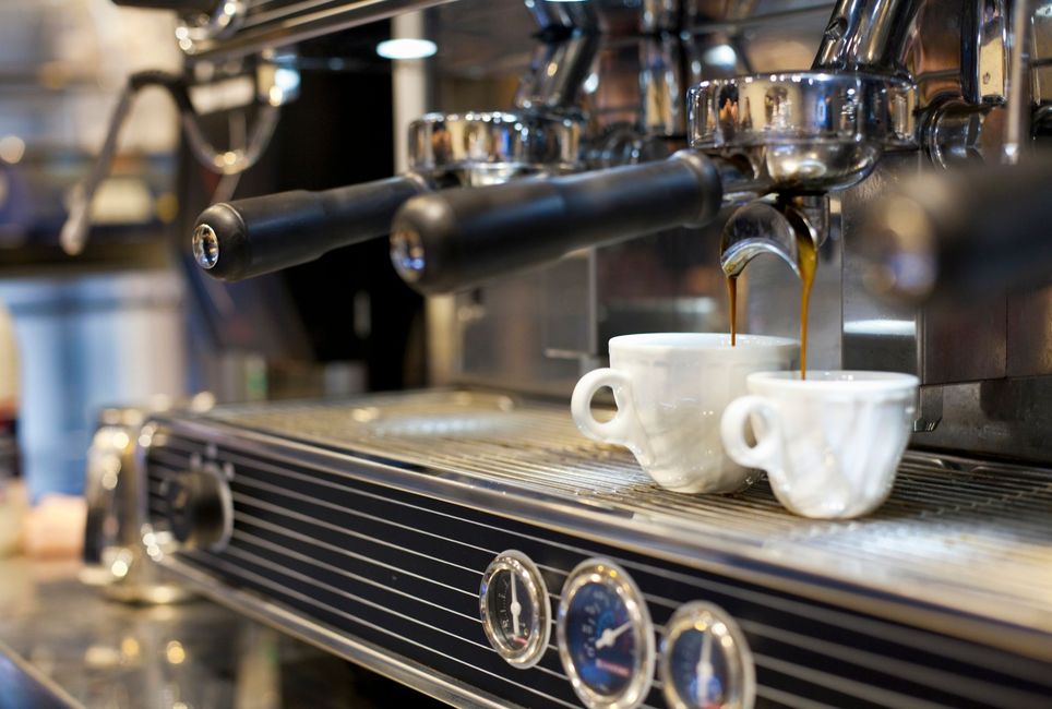 Due tazze di caffè vengono versate in una macchina per il caffè.