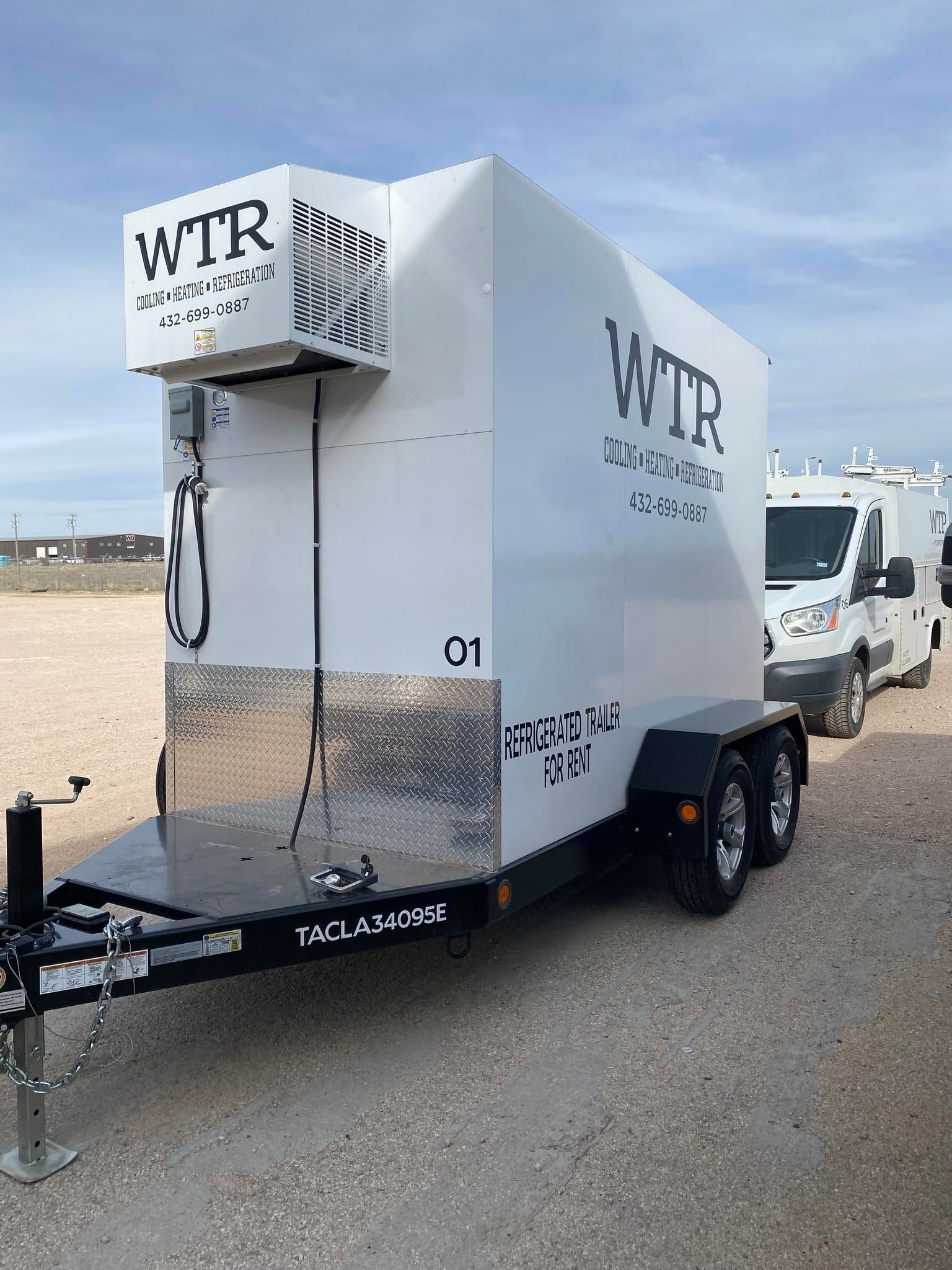 A white trailer with the word wtr on it is parked on the side of the road.