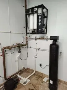 A room with pipes and a water filter on the wall.