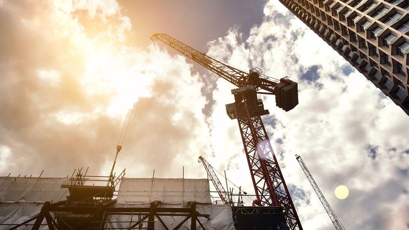 Un cantiere con una gru e un grattacielo sullo sfondo.