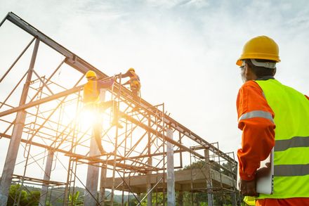 Un operaio edile è in piedi davanti a un edificio in costruzione.