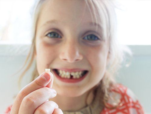 Teeth Extractions — Little Girl Holds Up Her Lost Tooth in Bangor, ME
