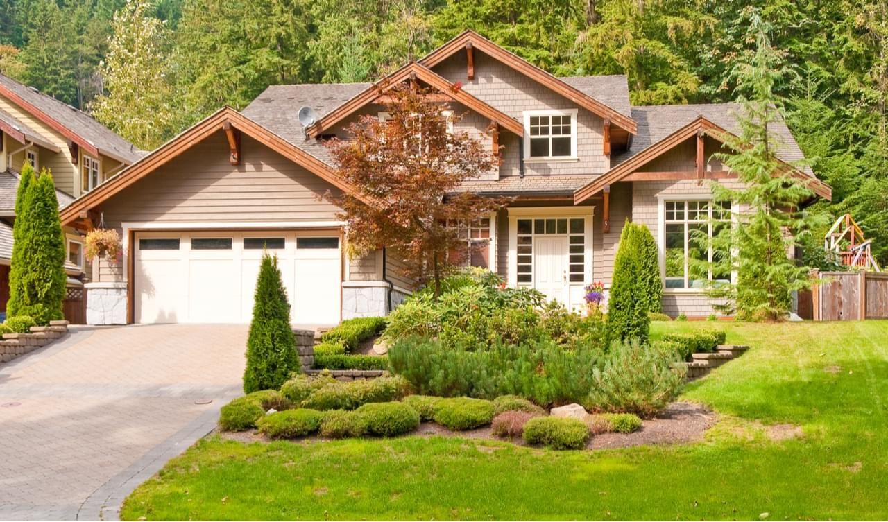 Brown suburban house with attached garage, manicured lawn, and landscaping.