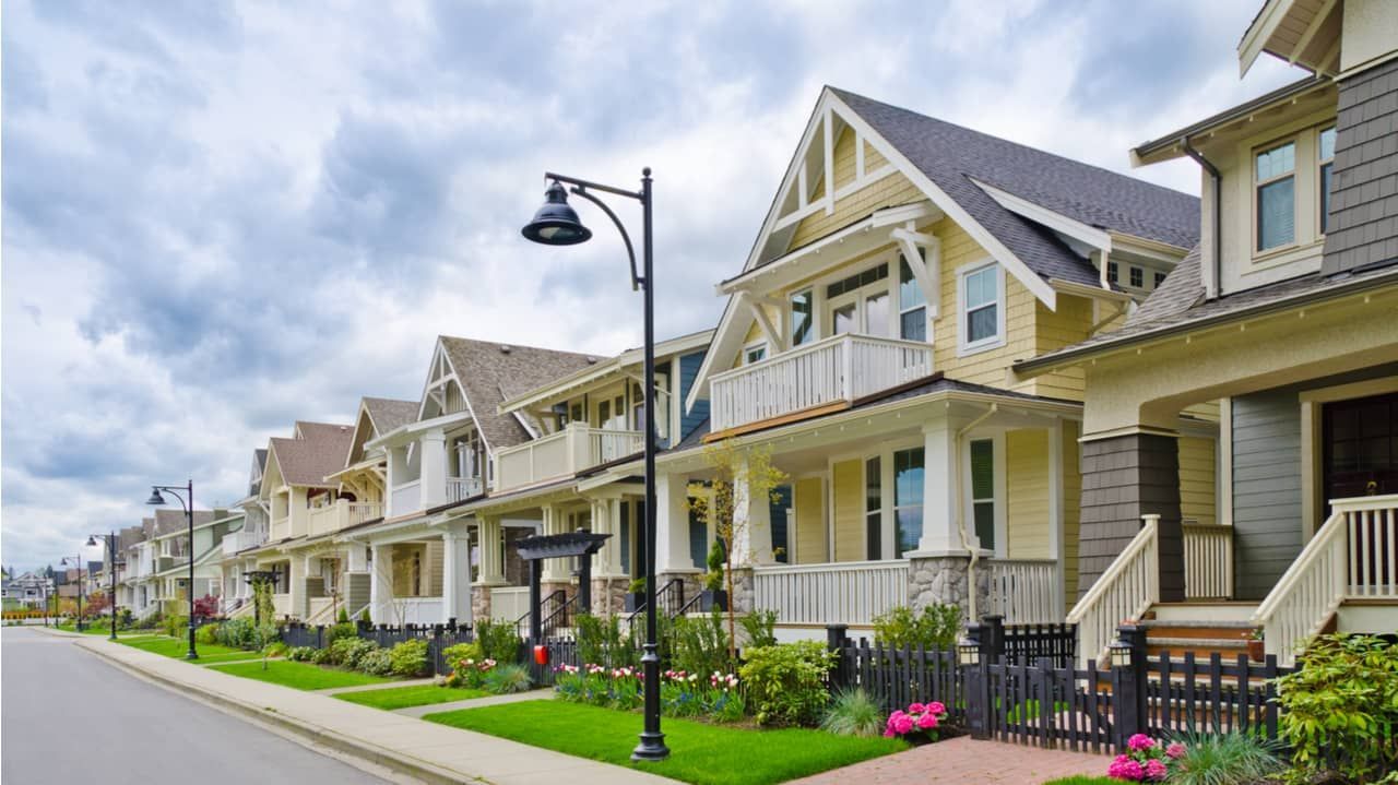 Row of colorful houses with varying designs, a street, and cloudy sky.