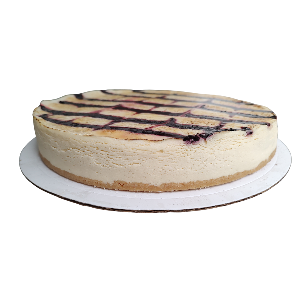 Tarta de queso sobre base de cartón blanco, cubierta con un chorrito de arándanos de Azúcar y Cacao