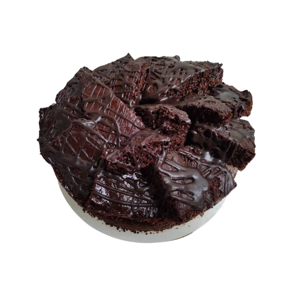 Pastel de chocolate con trozos de brownie encima, rociado con glaseado de chocolate, sobre un plato blanco de Azúcar y Cacao