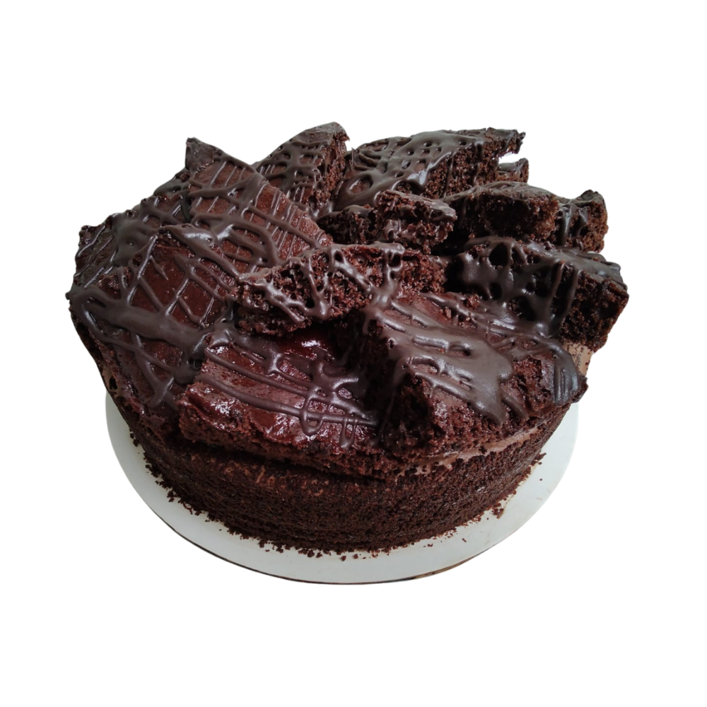 Pastel de chocolate con trozos de brownie encima, rociado con glaseado de chocolate, sobre un plato blanco de Azúcar y Cacao