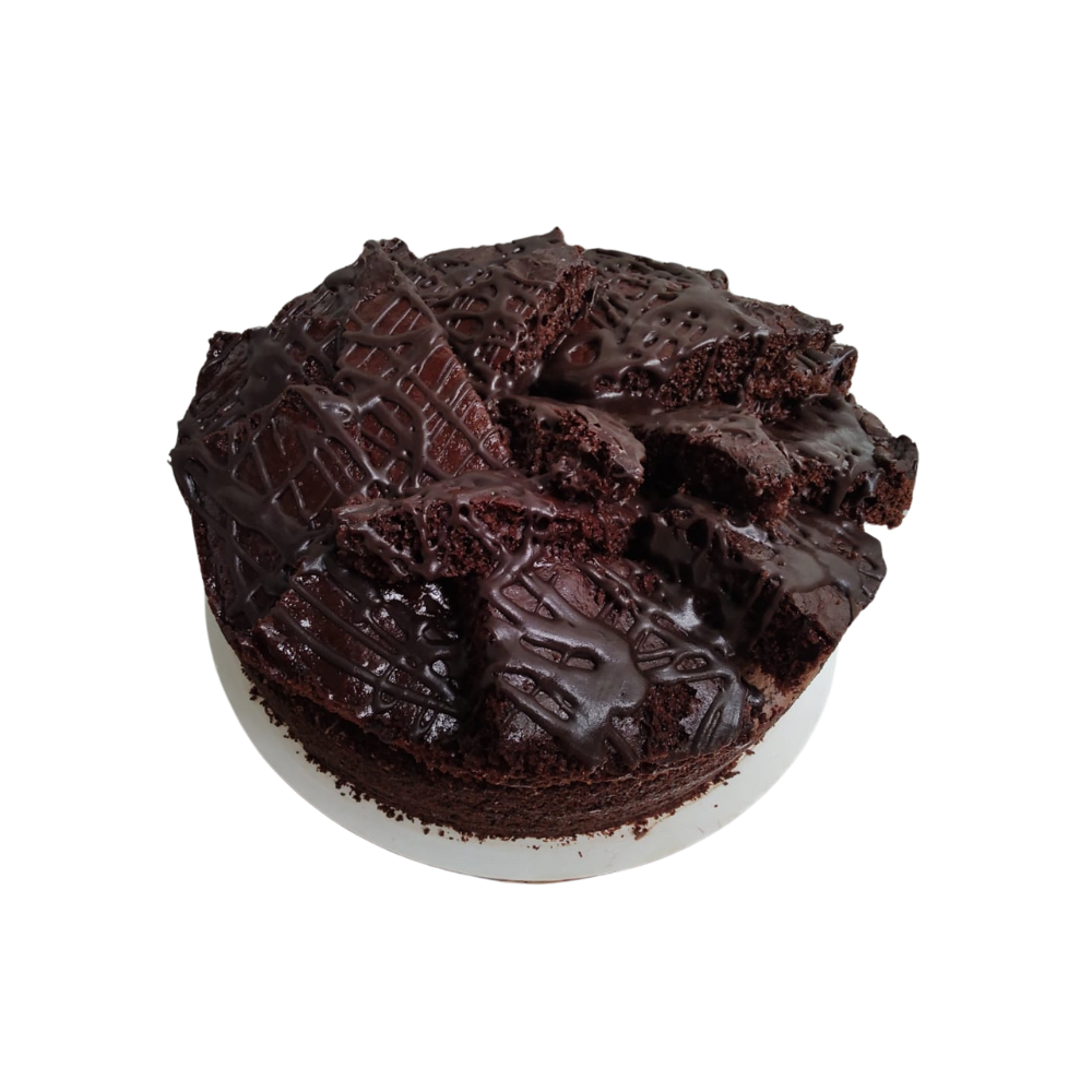 Pastel de chocolate con trozos de brownie encima, rociado con glaseado de chocolate, sobre un plato blanco de Azúcar y Cacao