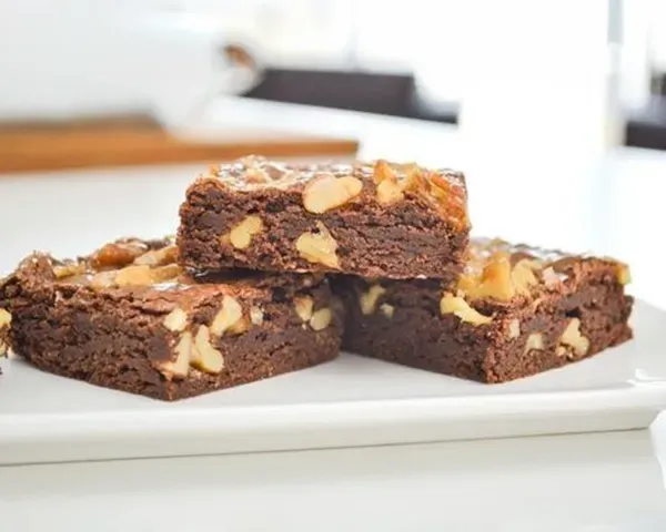 Tres brownies de nueces en un plato blanco de Azúcar y Cacao