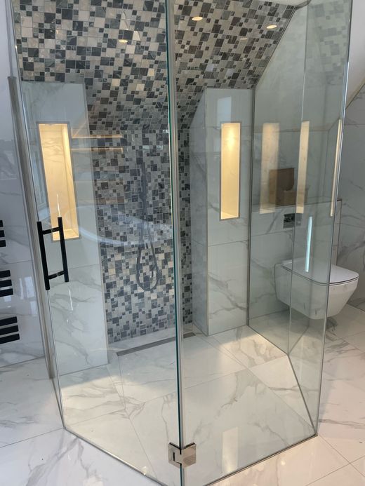 Modern bathroom with glass shower enclosure, tiled walls, and a floating toilet.