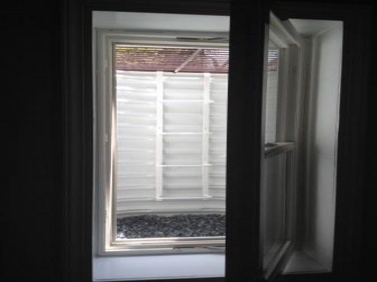 A window is open in a dark room with a fence in the background.