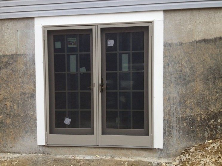 A window with a screen on it is on the side of a building.