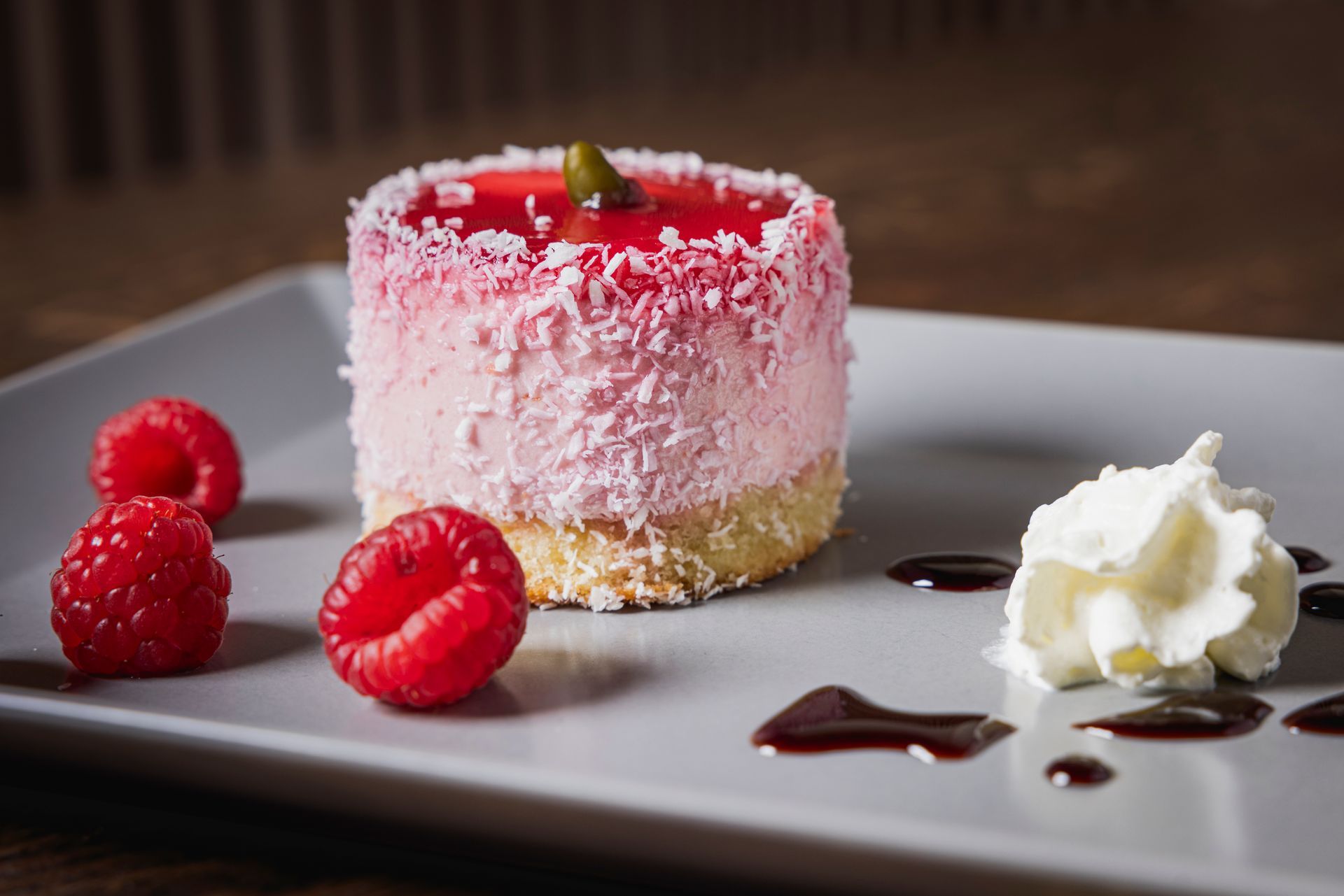 Ein Dessert mit Himbeeren und Schlagsahne auf einem Teller.