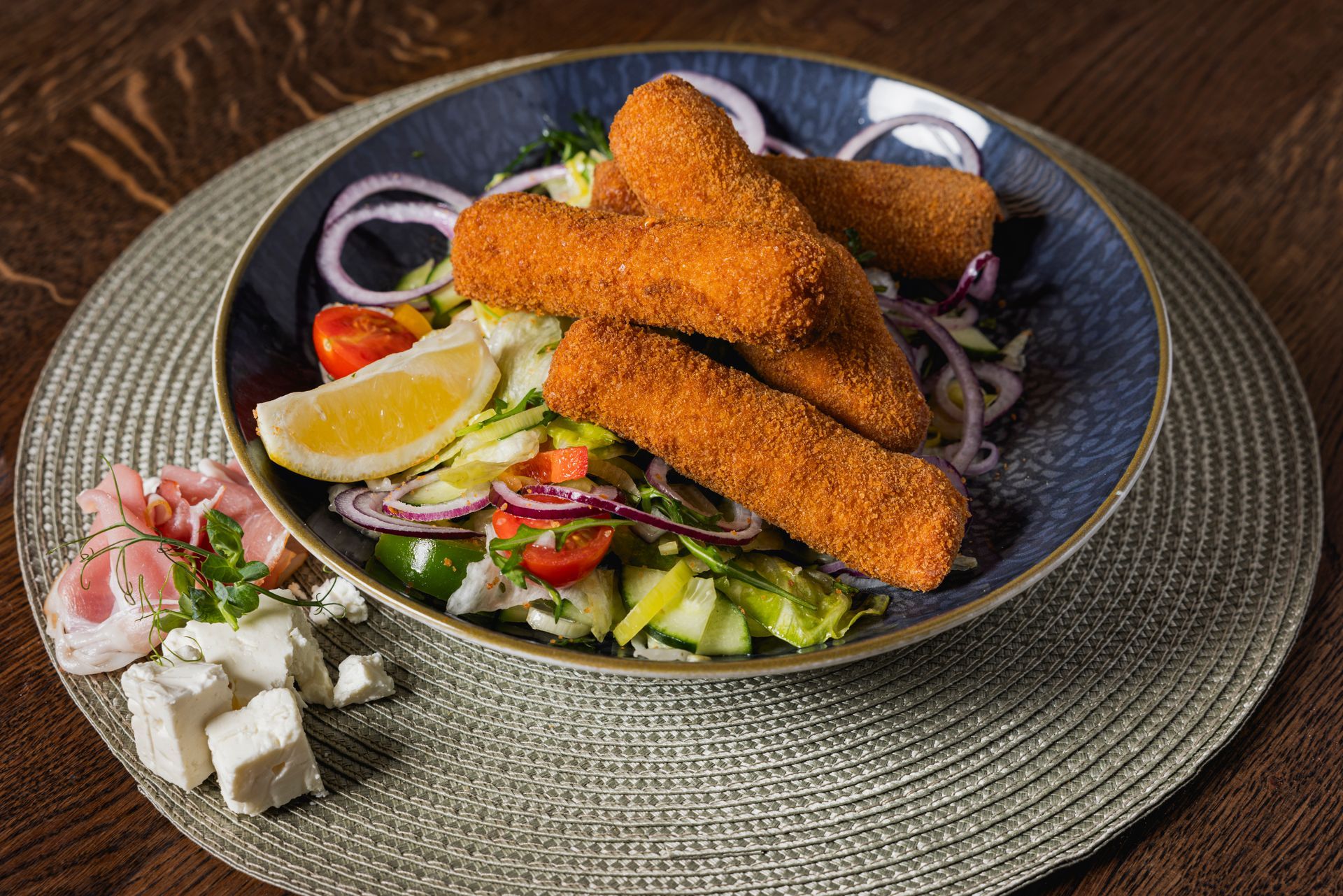 Ein Teller mit frittierten Fischstäbchen und Gemüse auf einem Tisch.