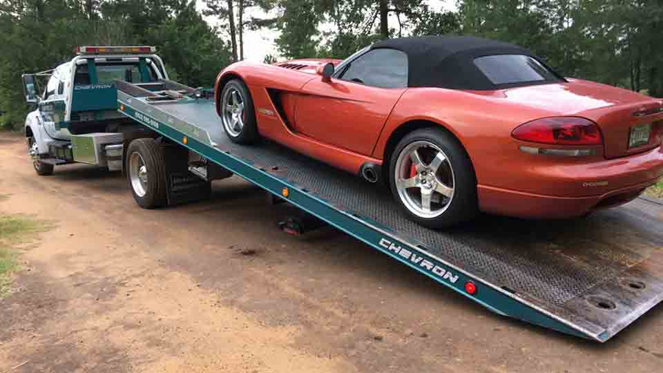 Tilt-bed truck carrying a sports car