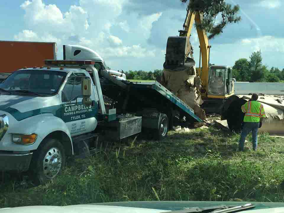 Tilt-bed truck with heavy equipment