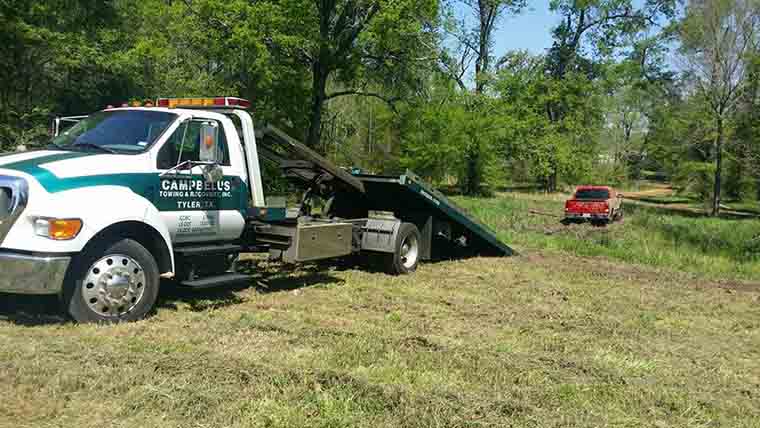Tow truck recovering pickup truck from woods