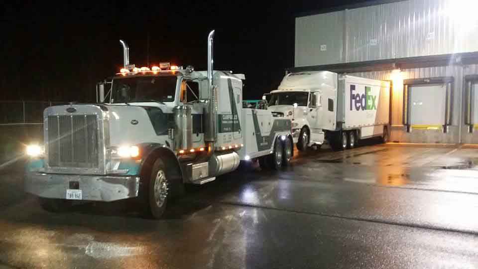 Heavy-duty tow truck hauling FedEx truck
