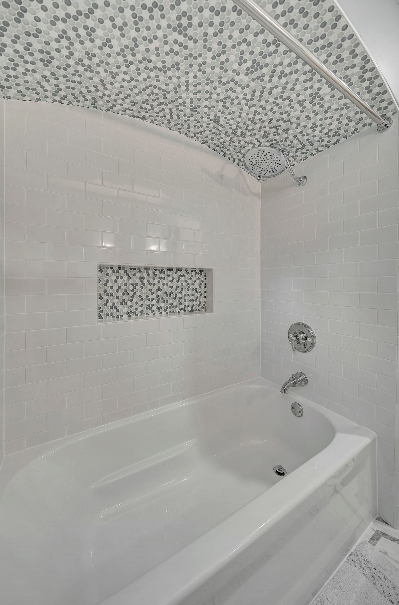 White tiled bathroom with mosaic ceiling and inset, centered tub.