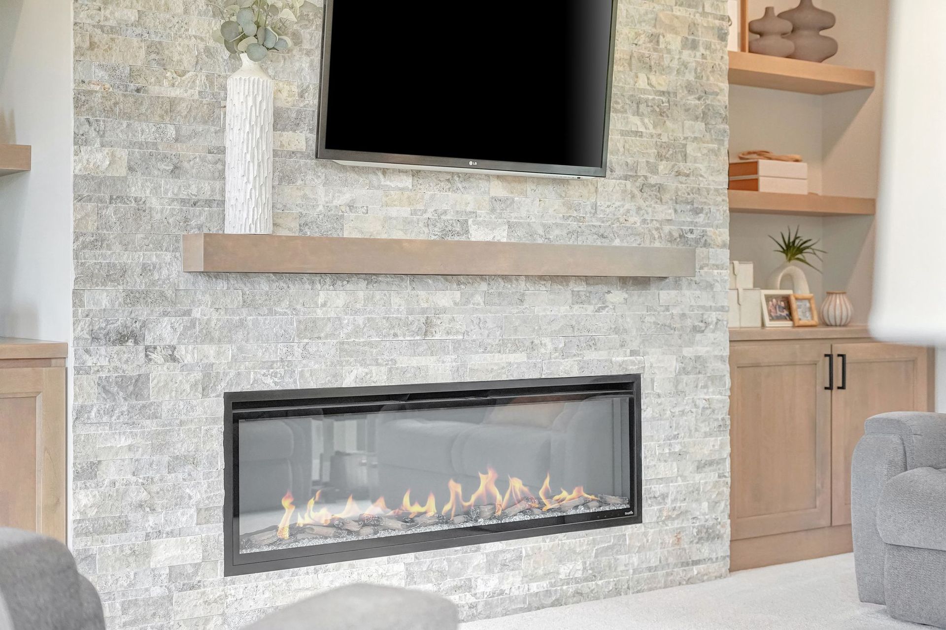 Fireplace with TV mounted above, gray stone wall, wooden shelf.