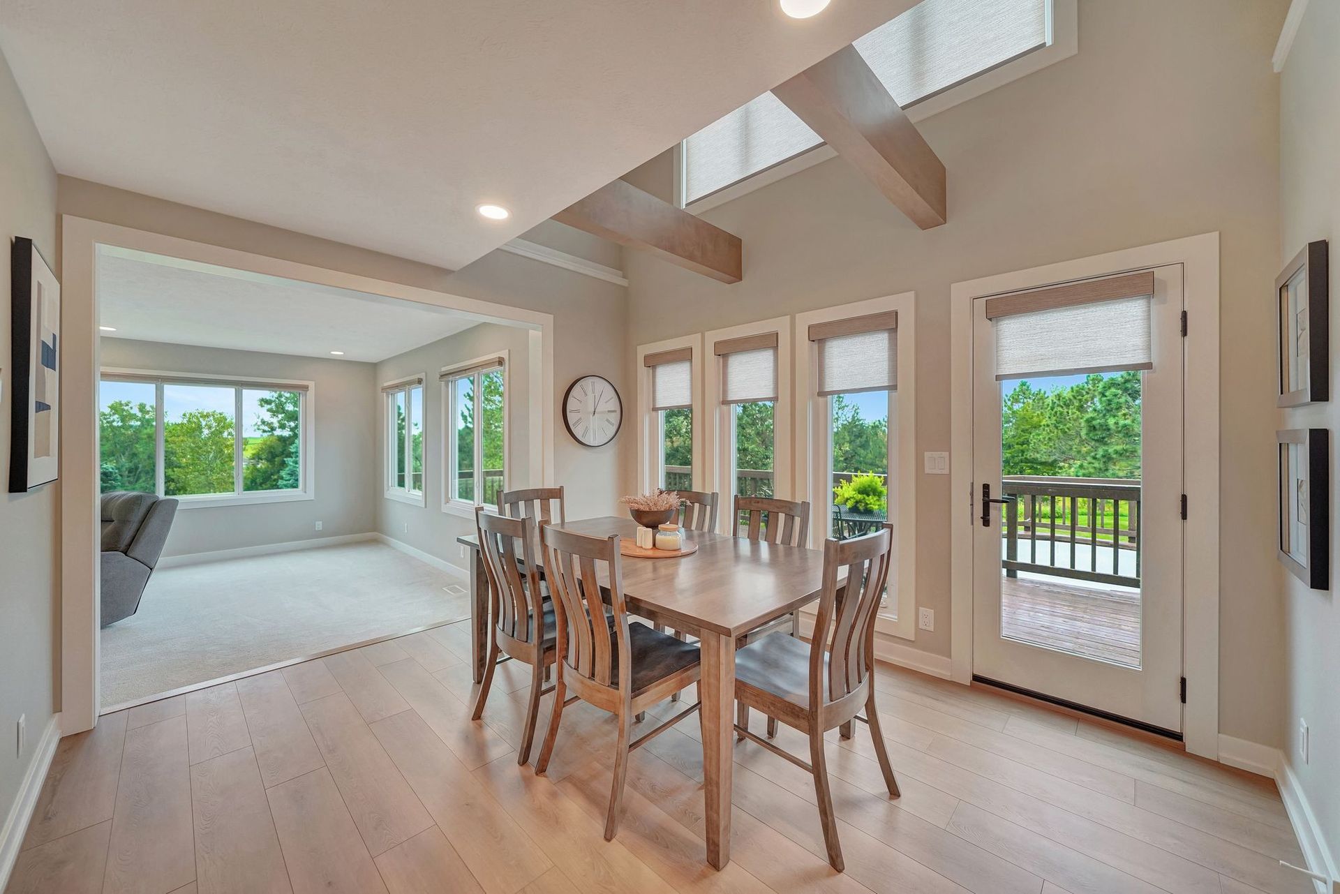 Dining room with wooden table and chairs, large windows, and an adjacent living area.