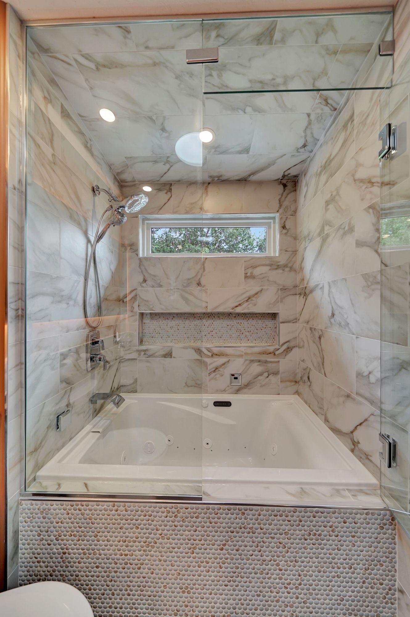 A bathroom with a tub and a shower with a glass door.
