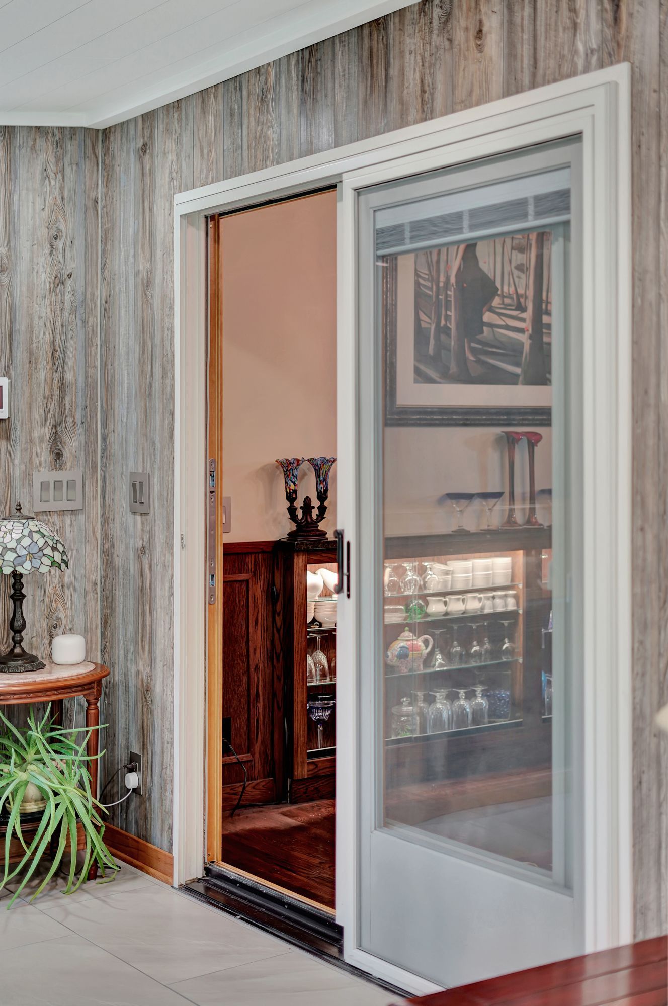 A sliding glass door with a screen is open to a living room.