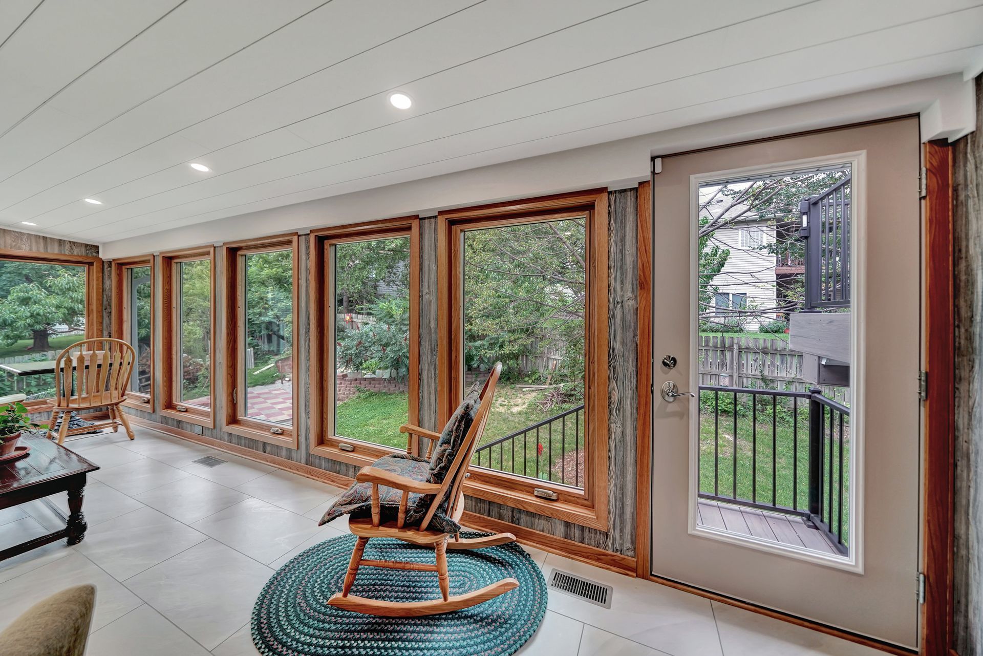 A living room with a rocking chair and a lot of windows.
