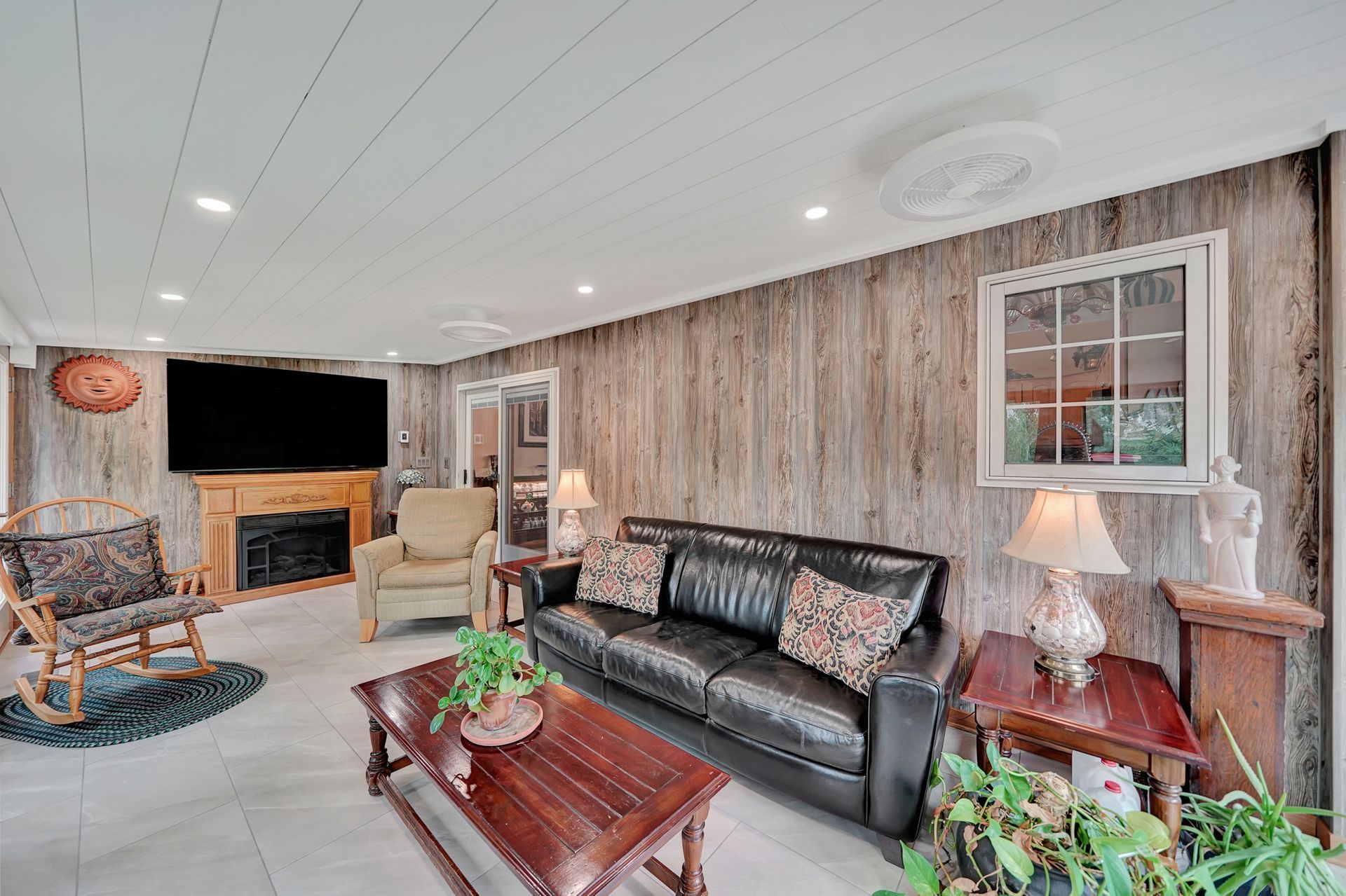 A living room with a couch , chairs , coffee table and television.