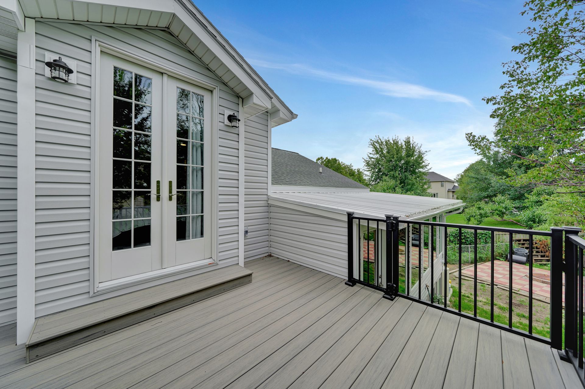 A deck with a railing and sliding glass doors on the side of a house.