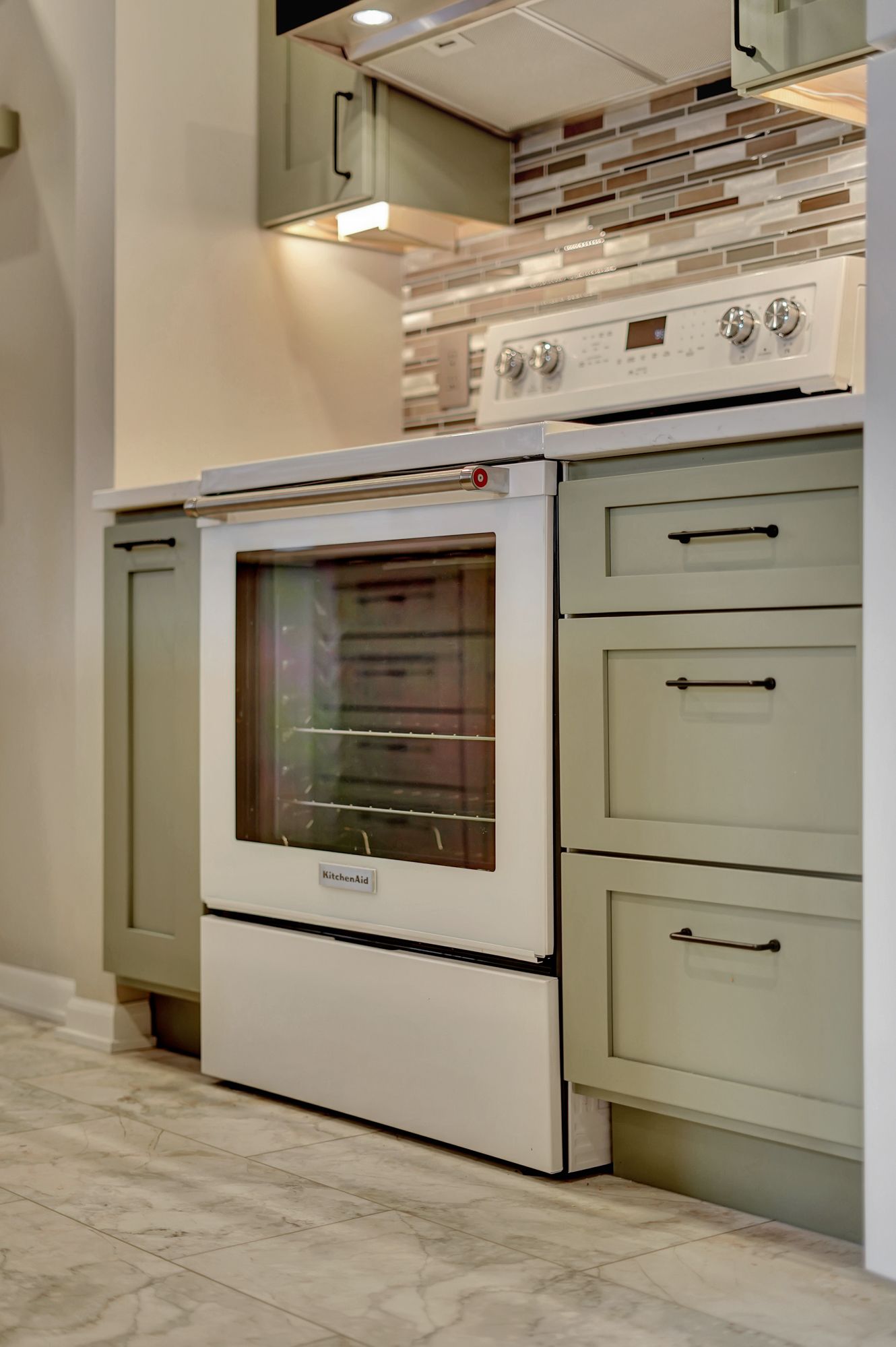 A white stove and oven in a kitchen with green cabinets | Lincoln, NE | SkyLimit Remodeling